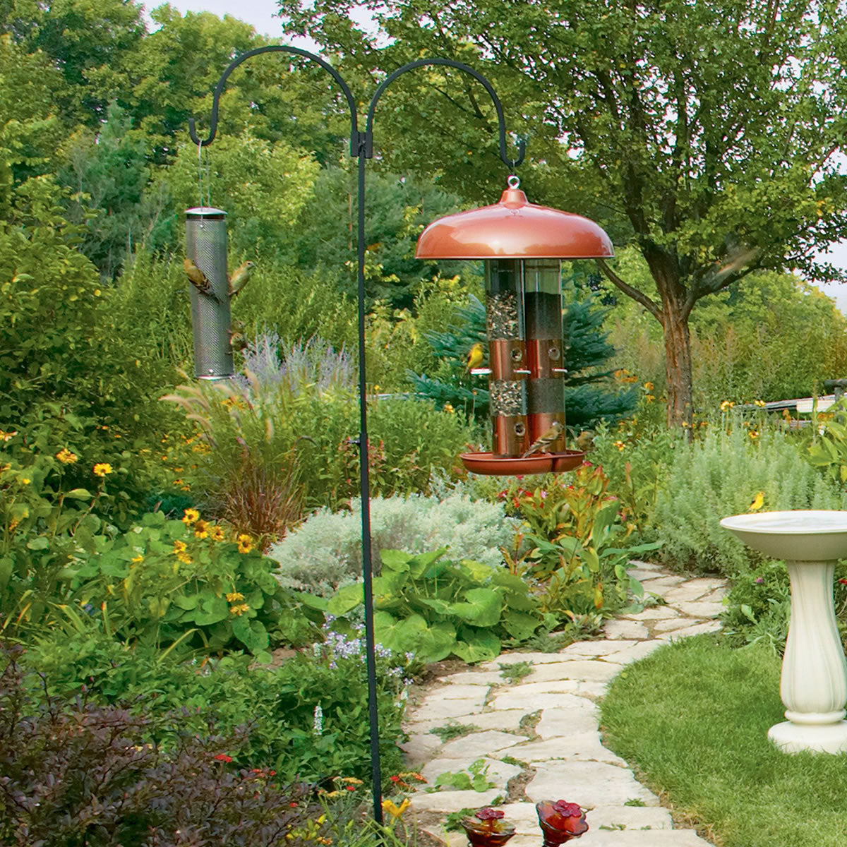 Adjustable Double Hanger in a garden, showcasing two arm hangers on a wrought iron pole designed to attract birds with stability and adjustable height.