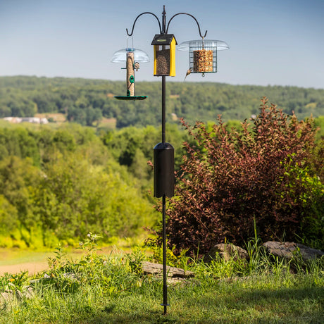 Squirrel-Proof Super Tall Quad Hanger featuring a three-arm pole with squirrel baffle, set in a grassy outdoor area, holds multiple bird feeders.